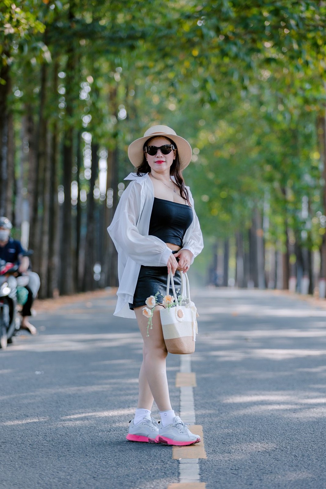Open white shirt, black bandeau, denim shorts, white trainers with pink soles, pale hat and white bag.