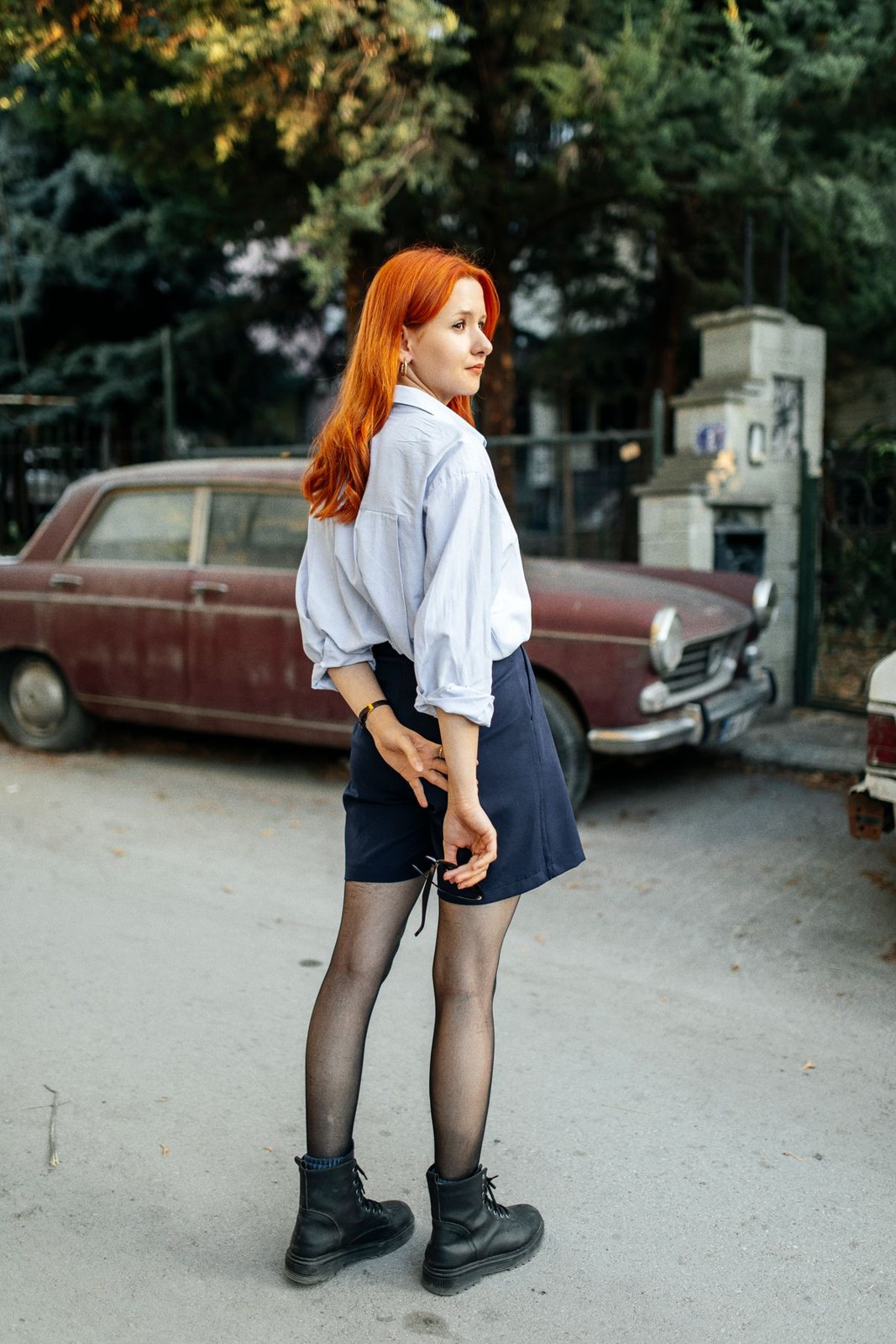 White shirt tucked into a navy miniskirt, with black tights and black lace-up ankle boots.