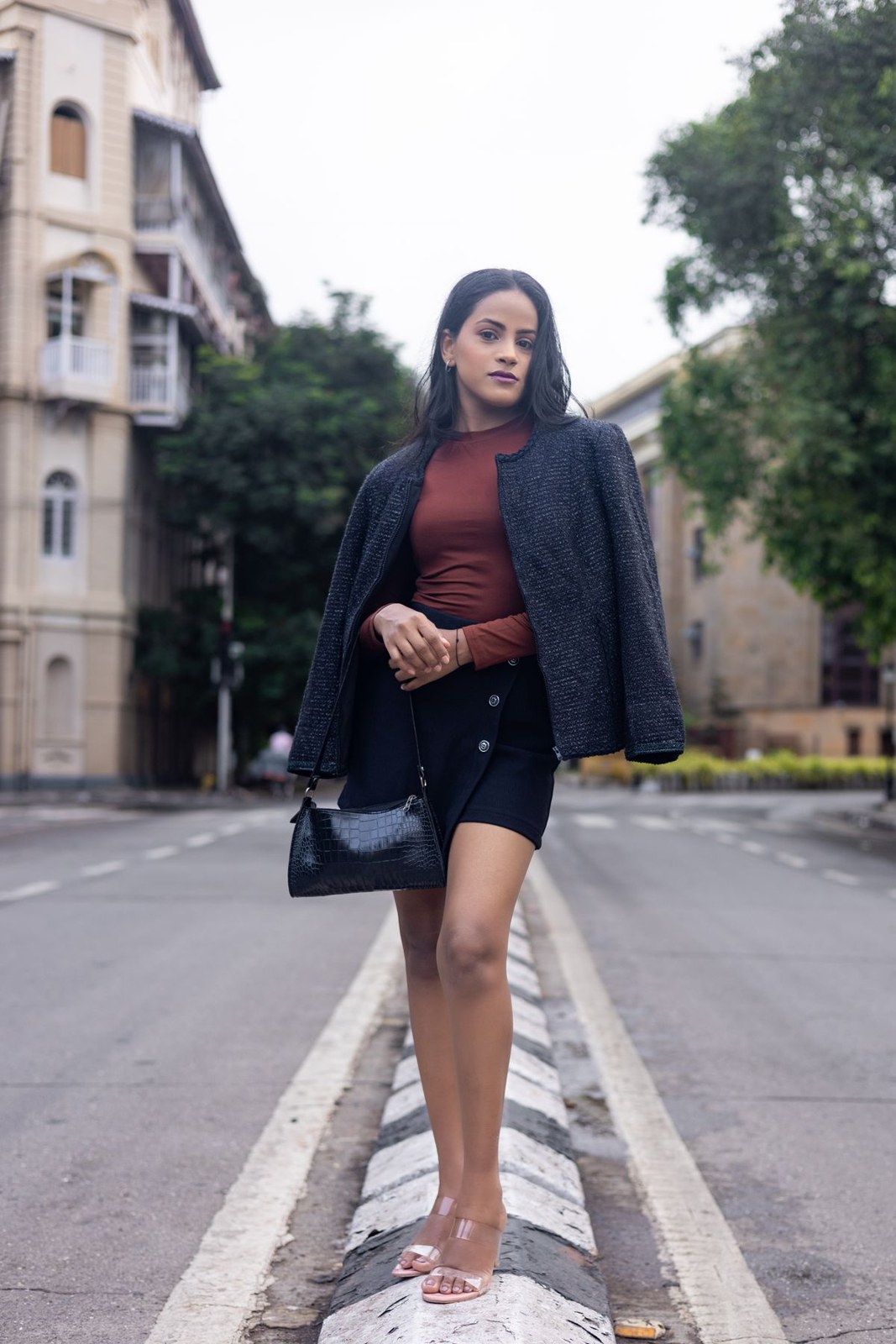 Navy blazer over a burgundy top, black cycling shorts, white trainers and a black handbag.