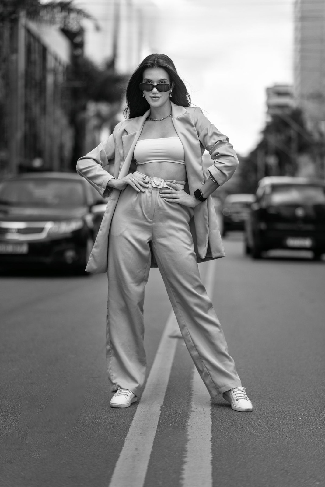 Black-and-white photo: loose matching blazer and trousers, light scoop-neck top, heels and sunglasses.