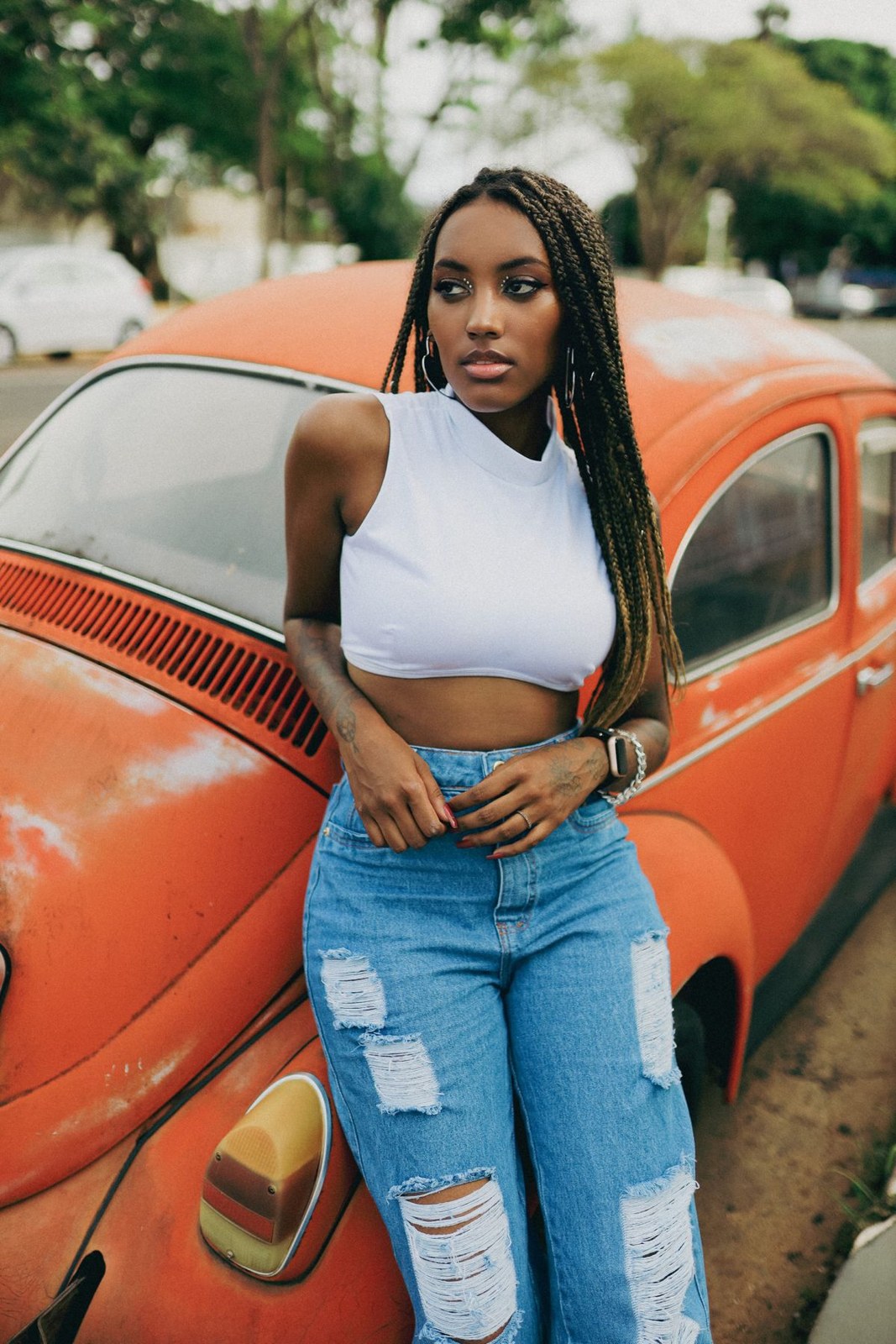 White high-neck sleeveless cropped top and ripped blue jeans, cropped above the knees.