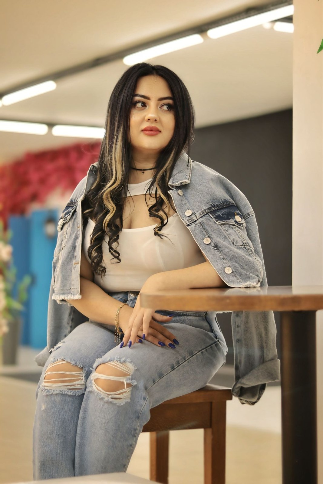 Denim jacket draped over a beige cropped top, ripped jeans and a small neck scarf.