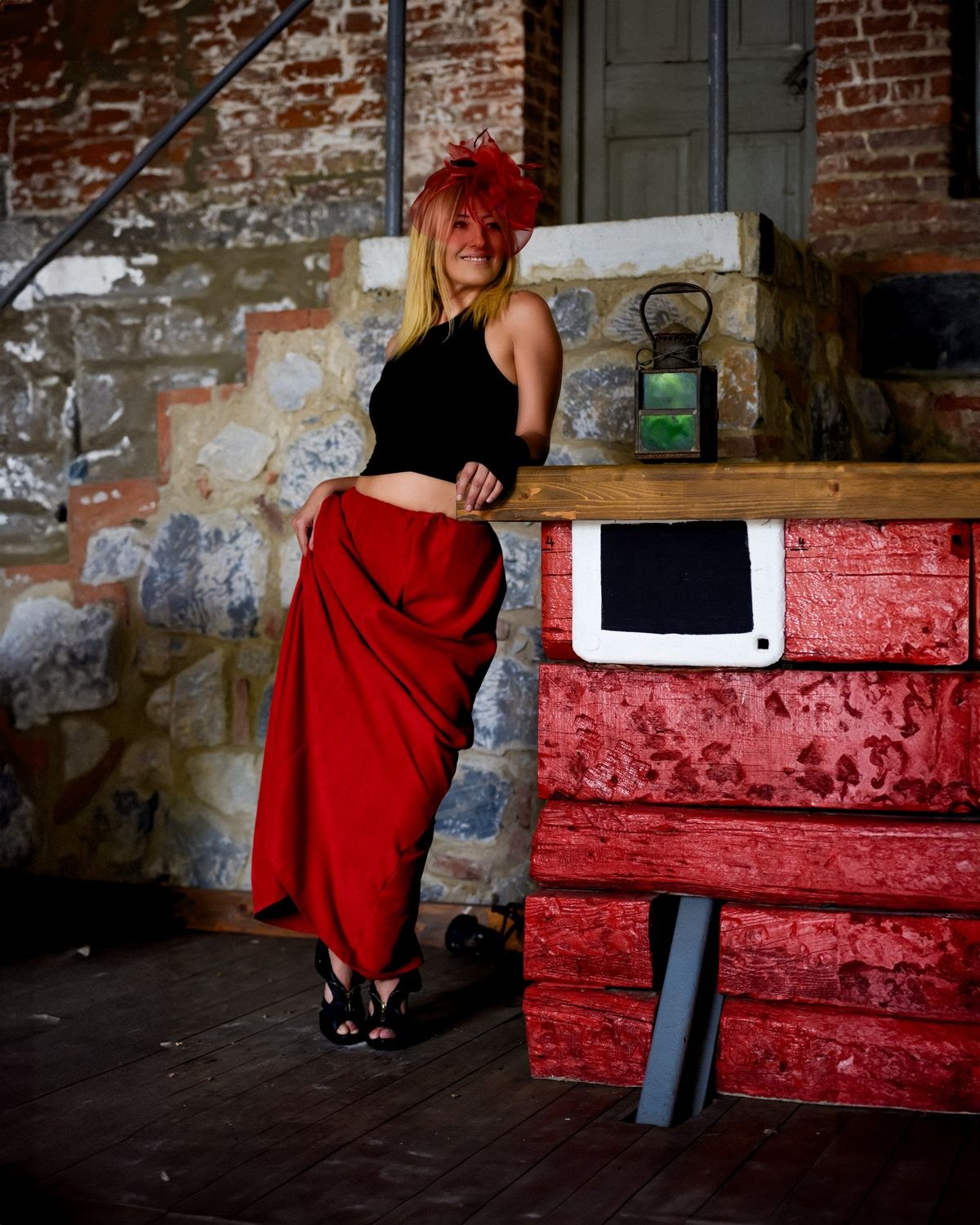 Black sleeveless cropped top, red draped midi skirt and chunky black shoes.
