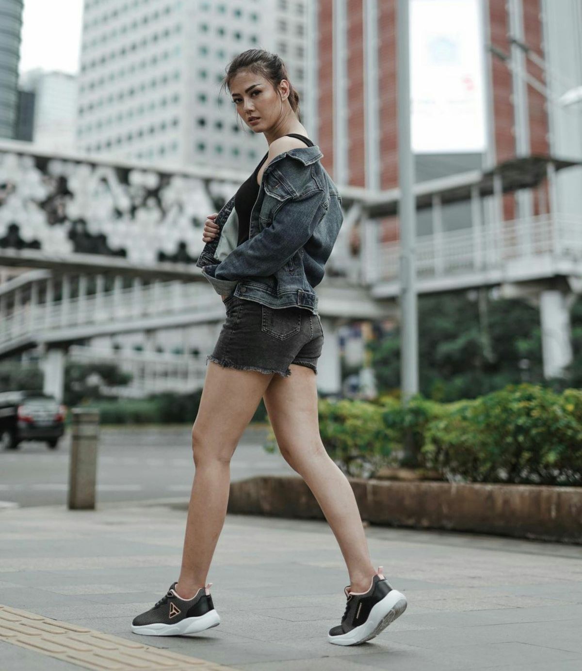 Dark denim jacket and matching short skirt with black low-top trainers.