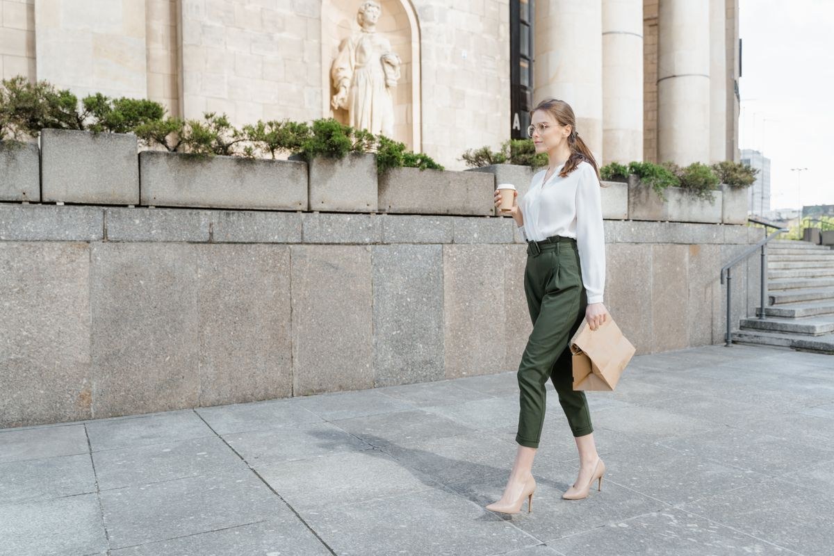 White blouse with olive cropped trousers, pale pointed heels and a small pale handbag.