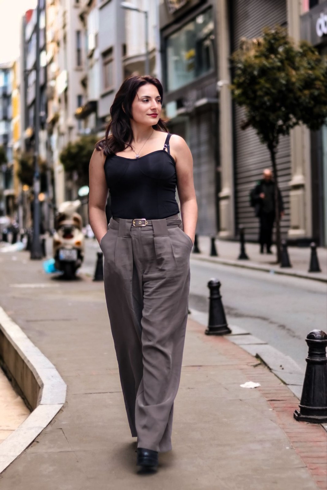 Black sleeveless square-neck top, grey pleated wide-leg trousers and black shoes.