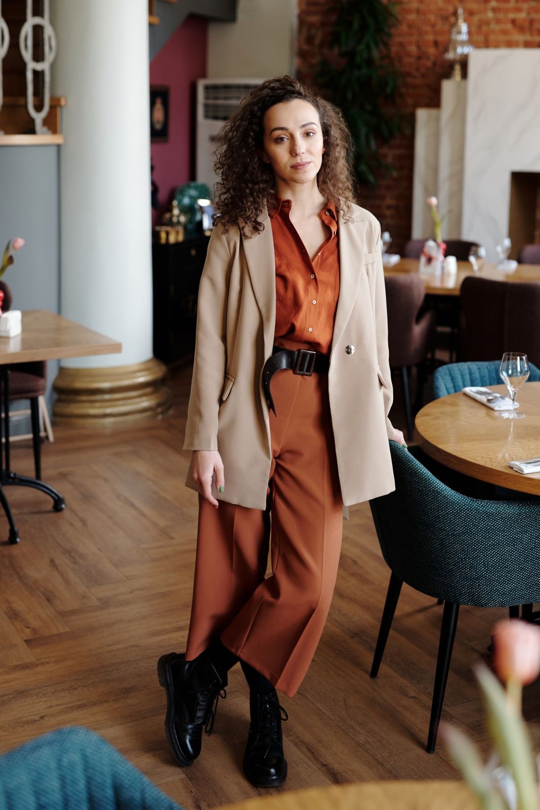 Beige blazer over a rust collared midi dress, wide black belt and black ankle boots.