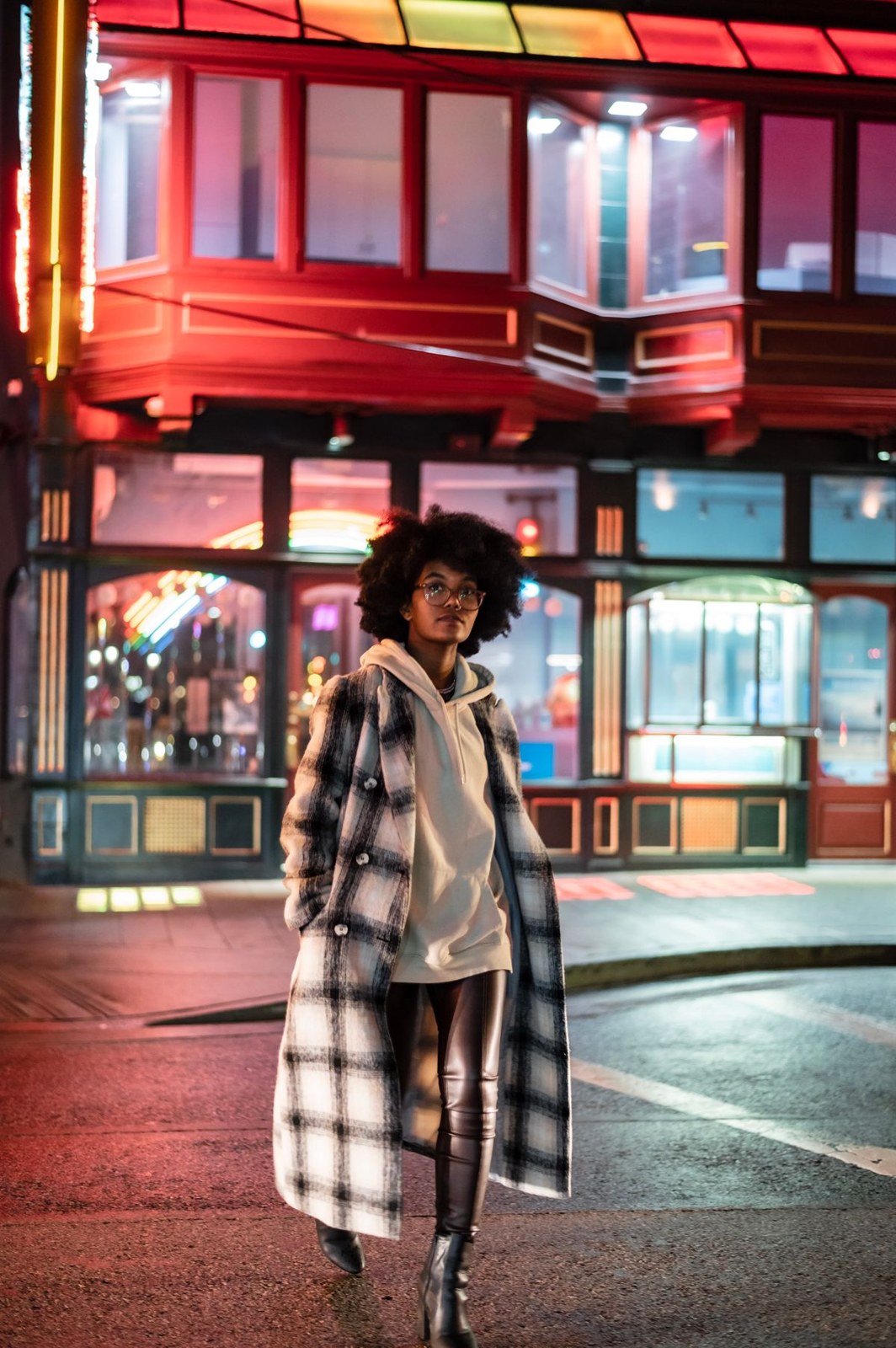 Long black-and-white checked coat over a pale high-neck top, short dark skirt and dark tall boots.