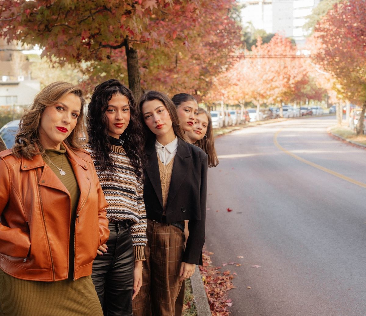 Group autumn portrait featuring a tan jacket, brown striped sweater and neutral blazers; lower legs not shown.