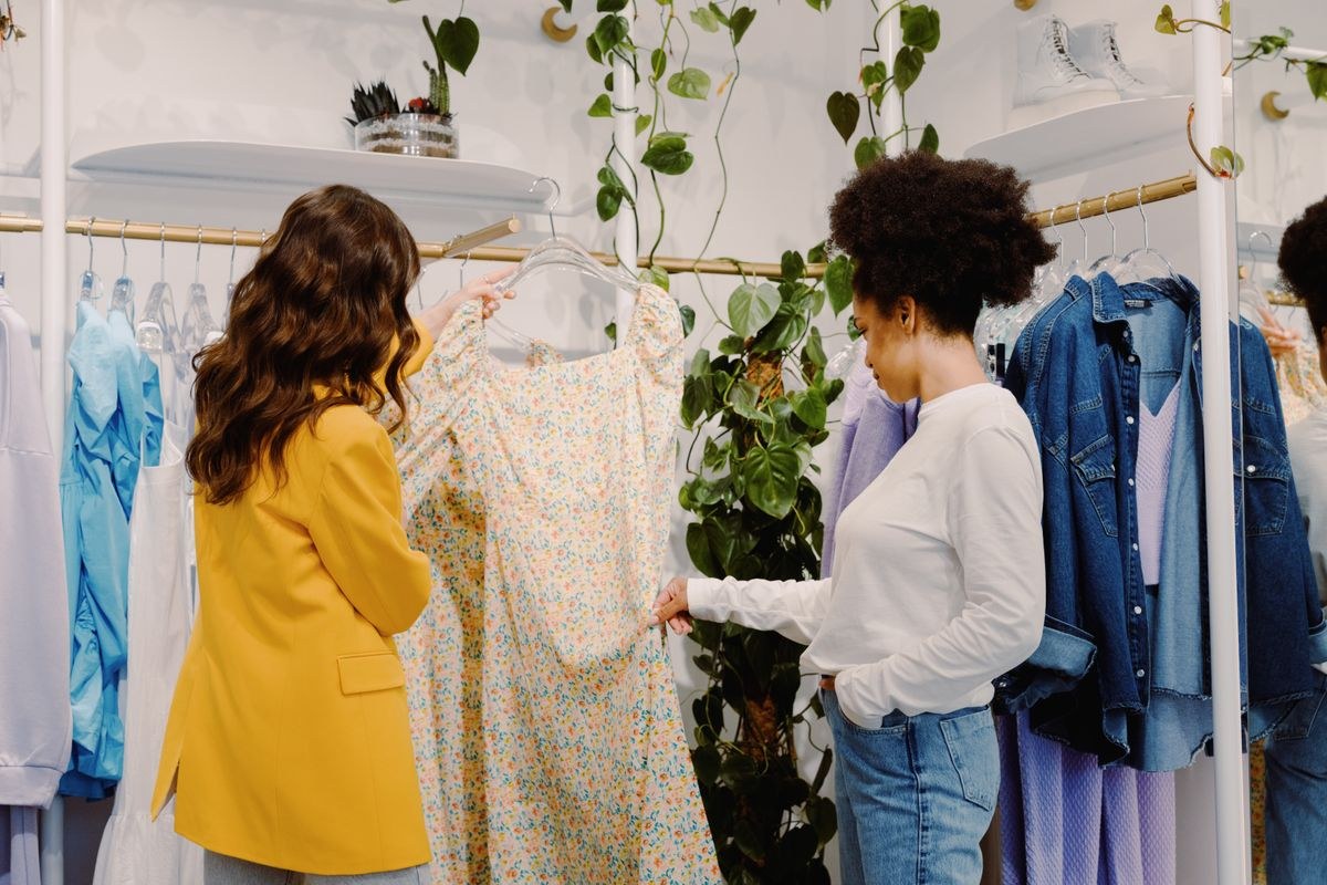 Yellow blazer and patterned light trousers beside a white blouse and blue jeans in a clothing shop.