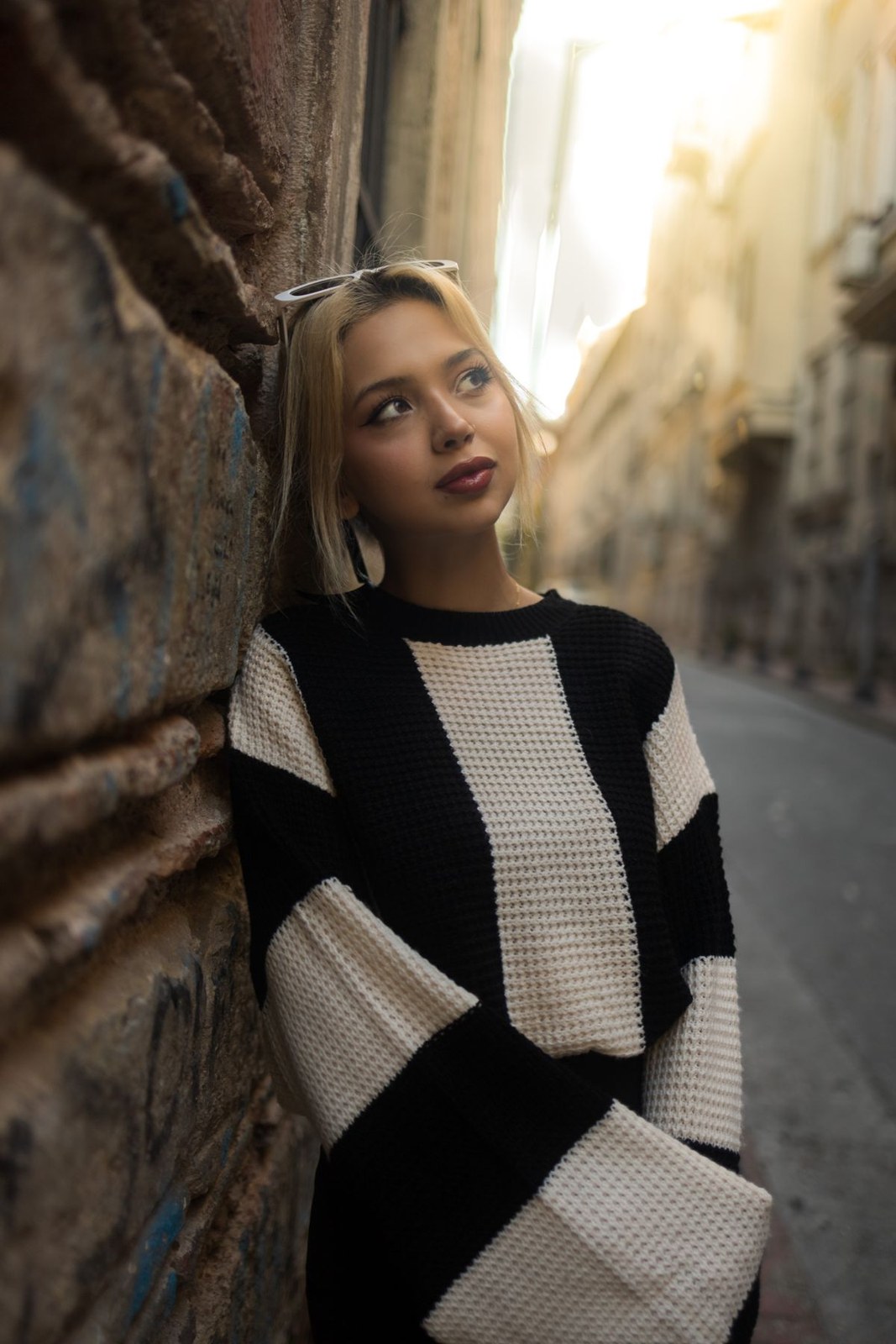 Black-and-cream block-pattern sweater in a narrow city street.