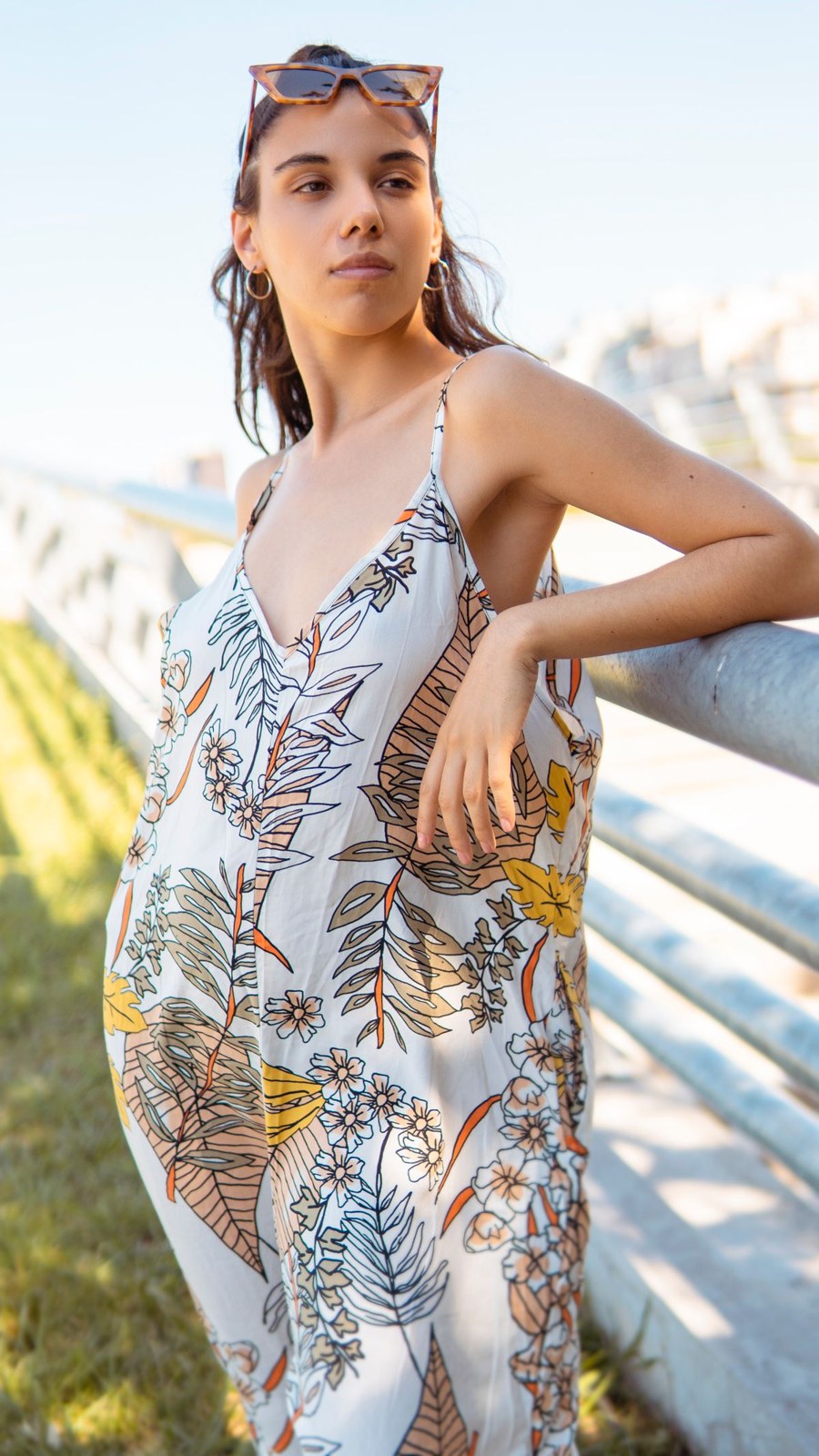 White loose sleeveless dress with a large botanical print beside a balcony railing.
