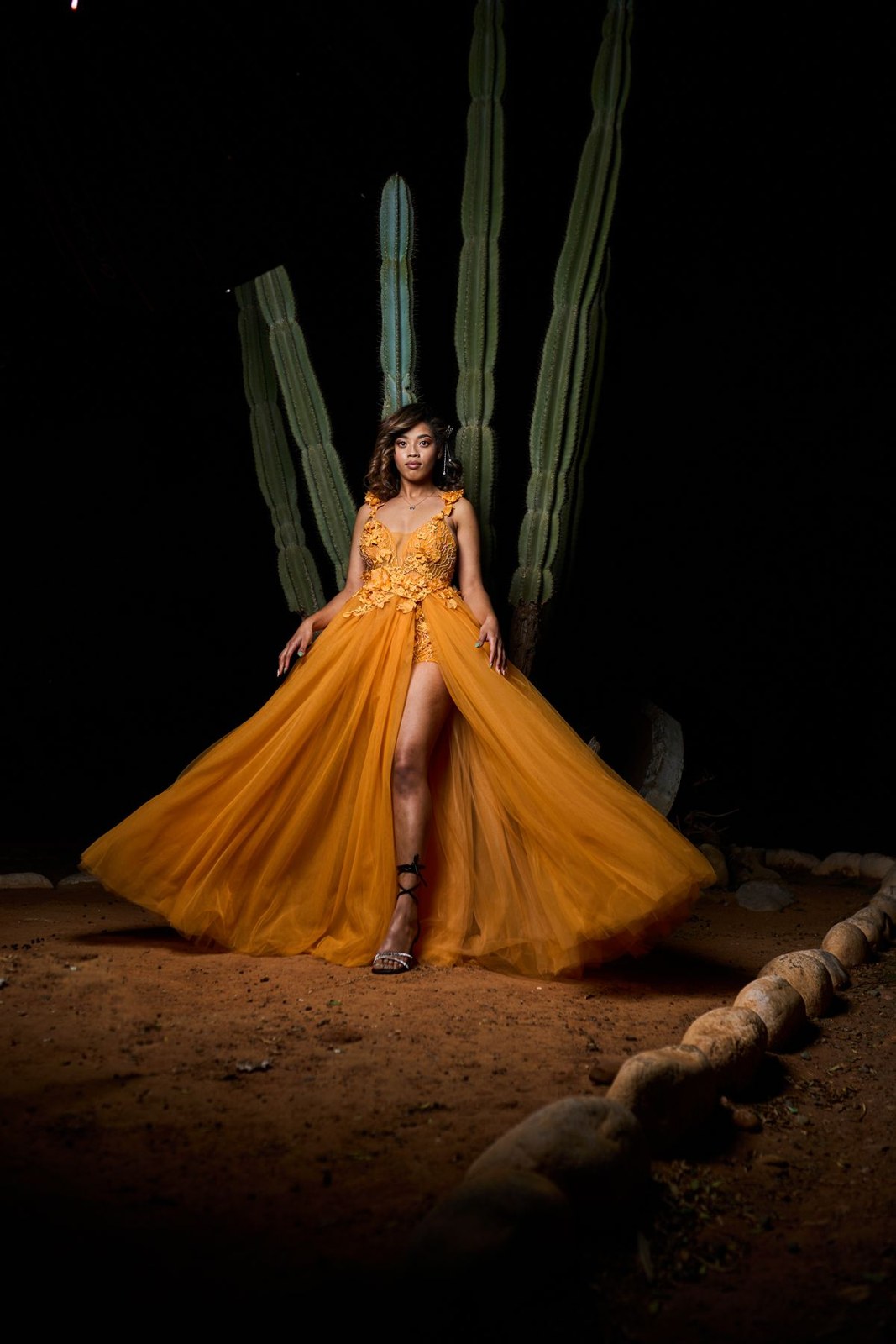 Yellow floor-length gown with a long flowing skirt and a slit, photographed at night.