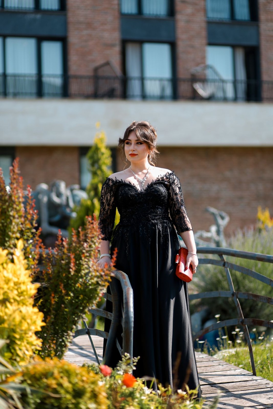 Long black gown with an embellished lace upper section and three-quarter sleeves outdoors.