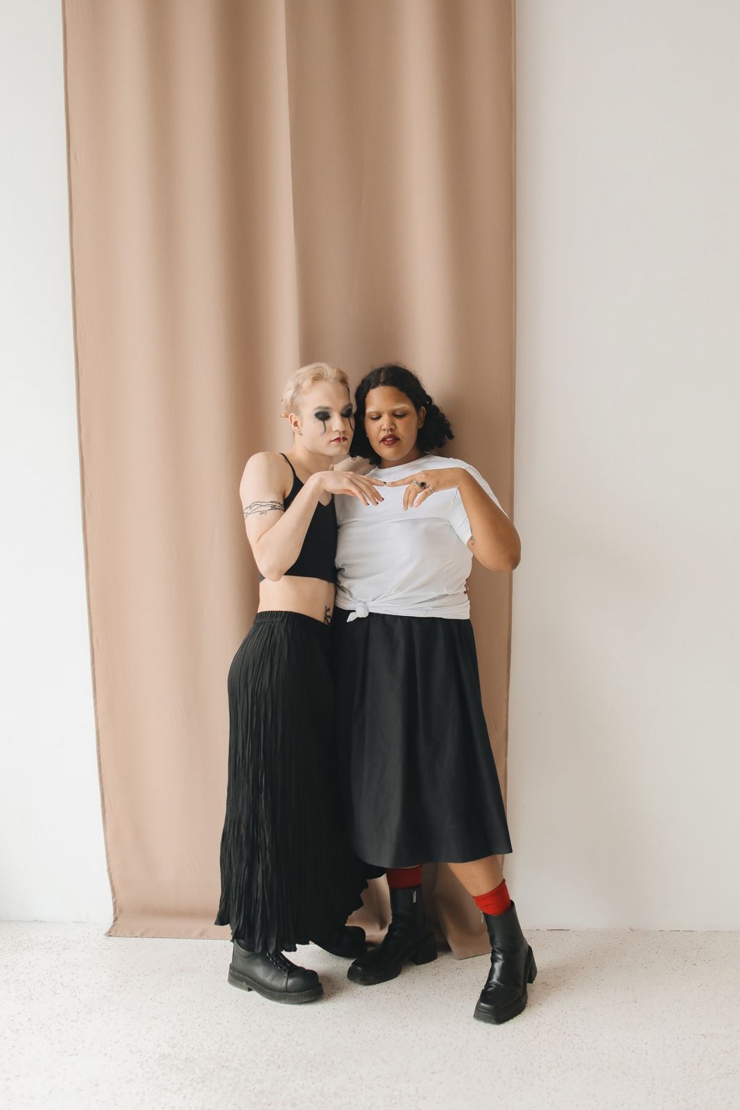 Two women in black and white tops, long dark skirts and black ankle boots.