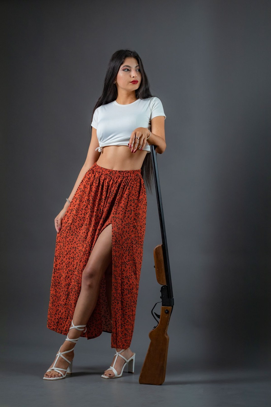Pale cropped T-shirt, long orange patterned skirt with a slit and pale lace-up heels.