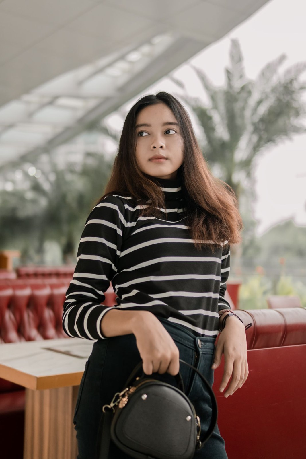 Black-and-white striped roll-neck top, black lower garment and a round black handbag.