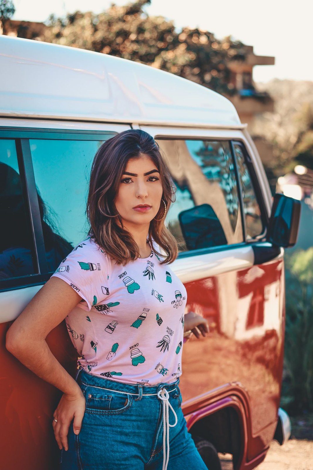 Pink printed short-sleeve T-shirt tucked into high-waisted blue jeans with a tied waist cord.