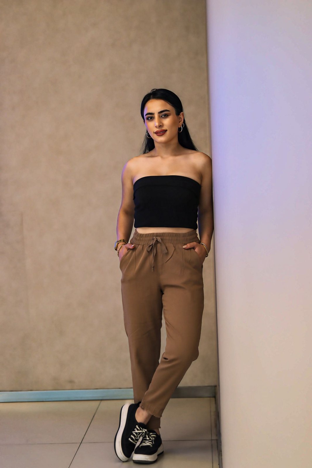 Black strapless cropped top, tan tapered trousers and black-and-white trainers.