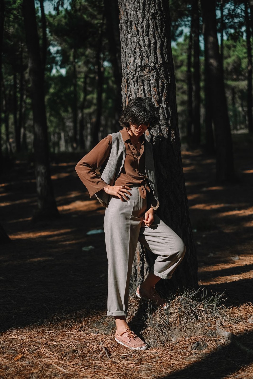 Tan blazer over a light collared blouse, pale loose trousers and bare feet in a forest.